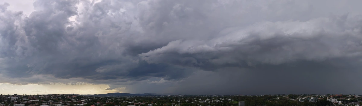 An aerial panorama of the suburban brisbane skyline, taken by drone, showing a dark storm rolling in