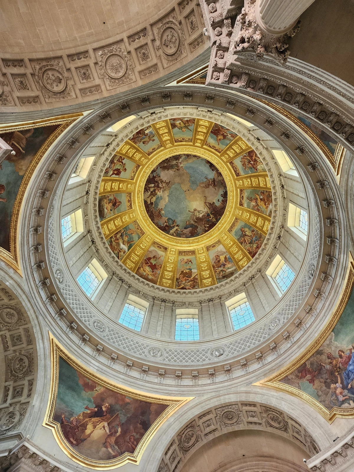 "looking up at the large dome, with frescoes and arches below the base and 12 windows encircling the dome\u0027s bottom level. above each window is a fresco of a biblical scene, and the center of the dome is a large circular fresco"
